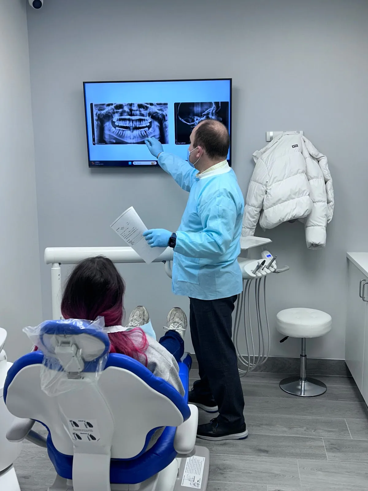 Dr. Boris Pinhasov walking a patient through their panoramic X-ray and treatment plan on the operatory screen.